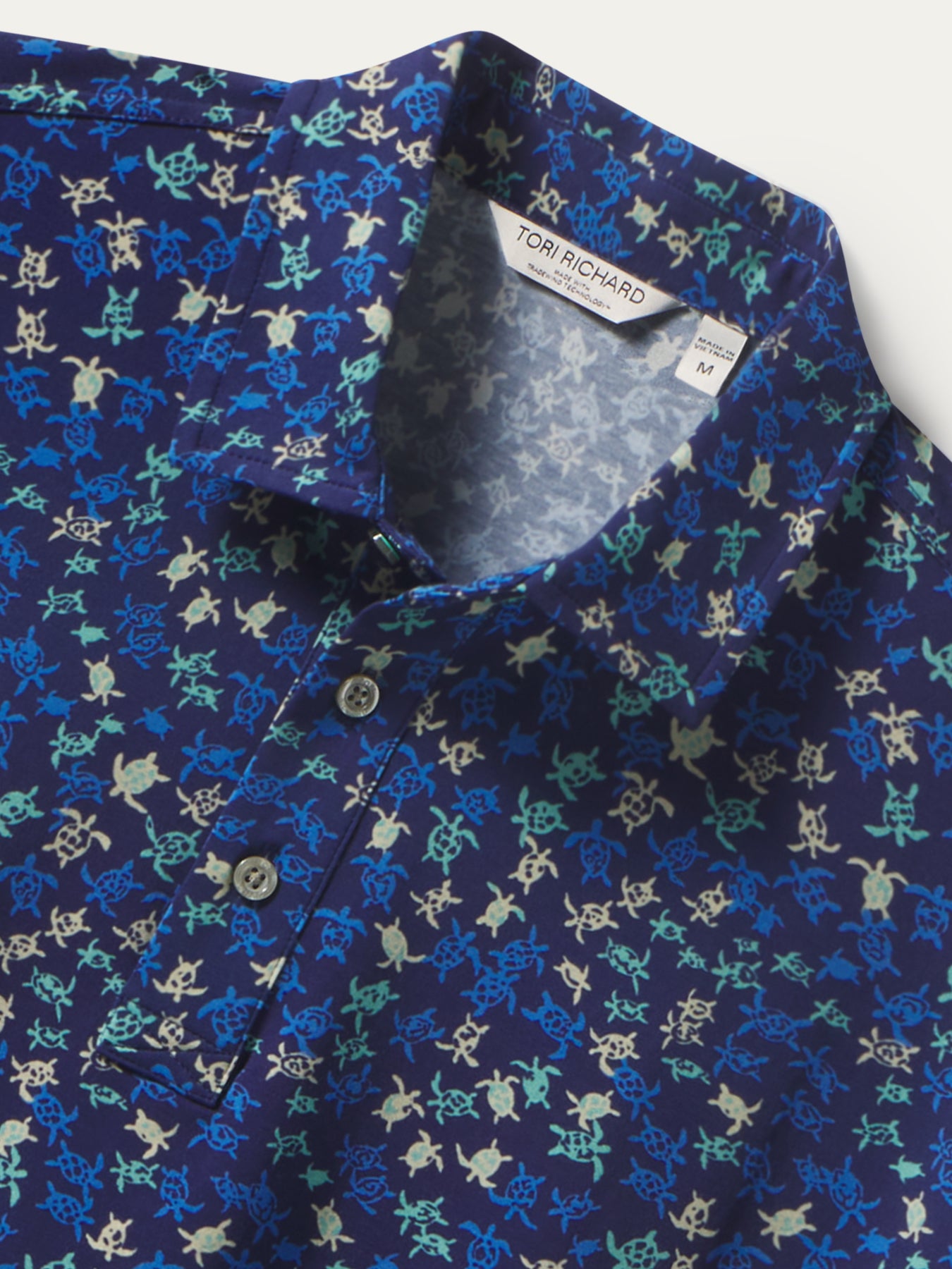 Blue honu hatchlings print polo shirt with three buttons, front view shown in both images.