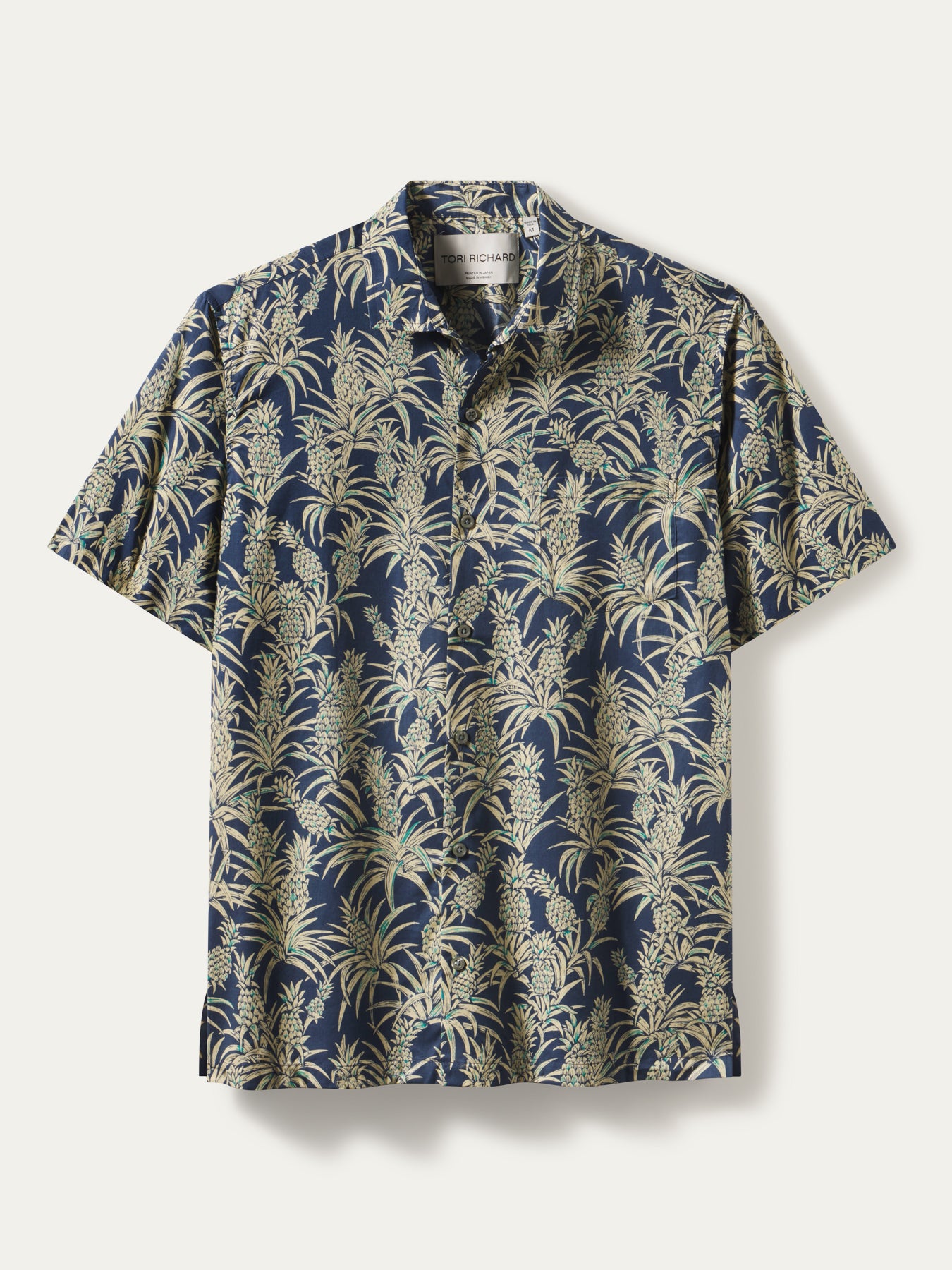 Navy shirt with beige and green tropical leaf and pineapple print, front view.