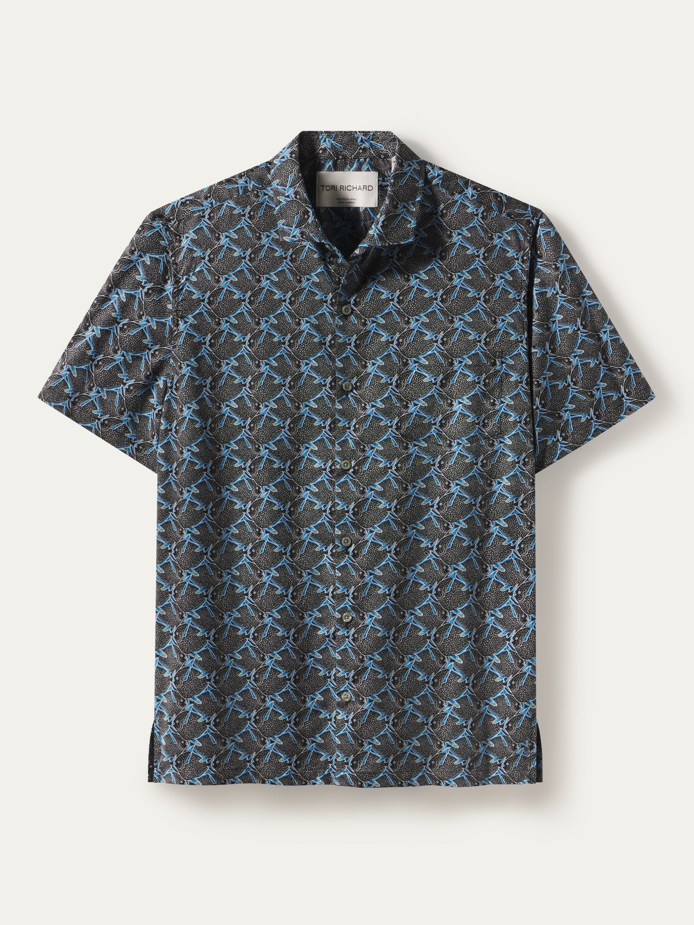 A short-sleeve button-up shirt with a dark gray and black background covered in a repeating light blue graphic pattern, displayed flat against a light off-white background.