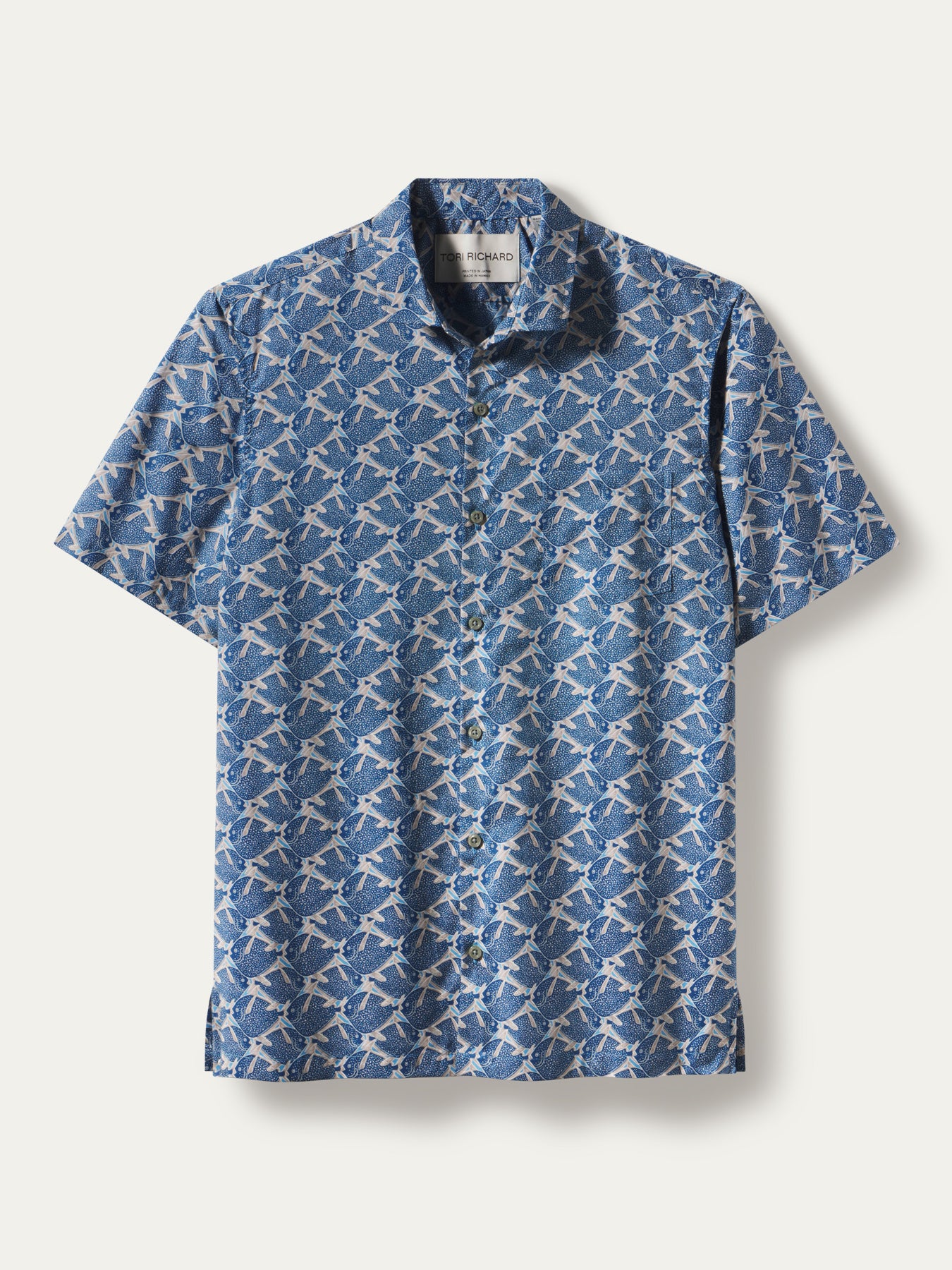A short-sleeve button-up shirt with a blue and white repeating geometric pattern, displayed flat against a light beige background.