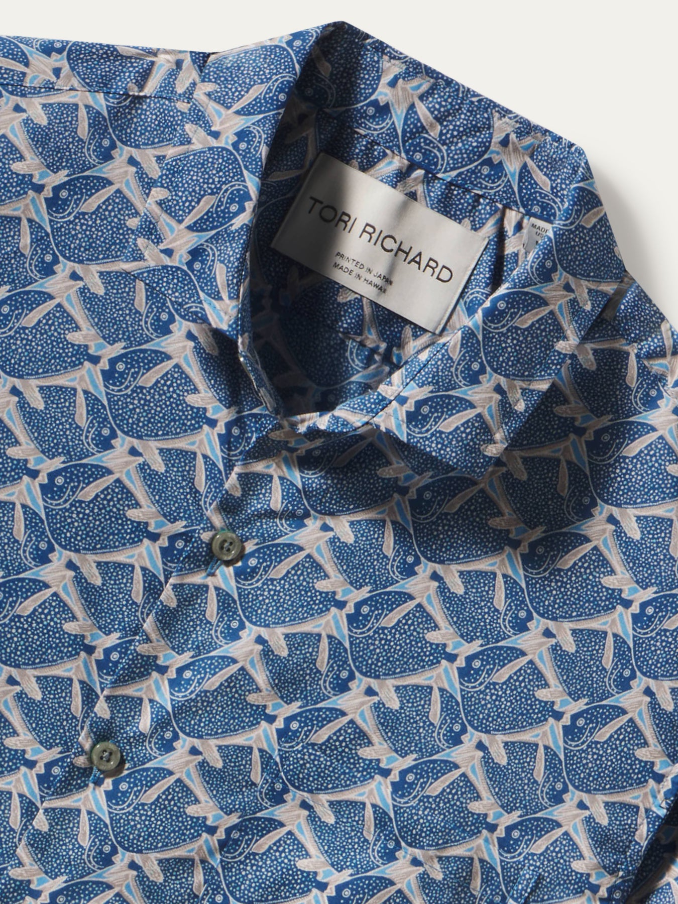 Close-up of a blue and white patterned button-down shirt by Tori Richard, showing the collar label and part of the fabric print.