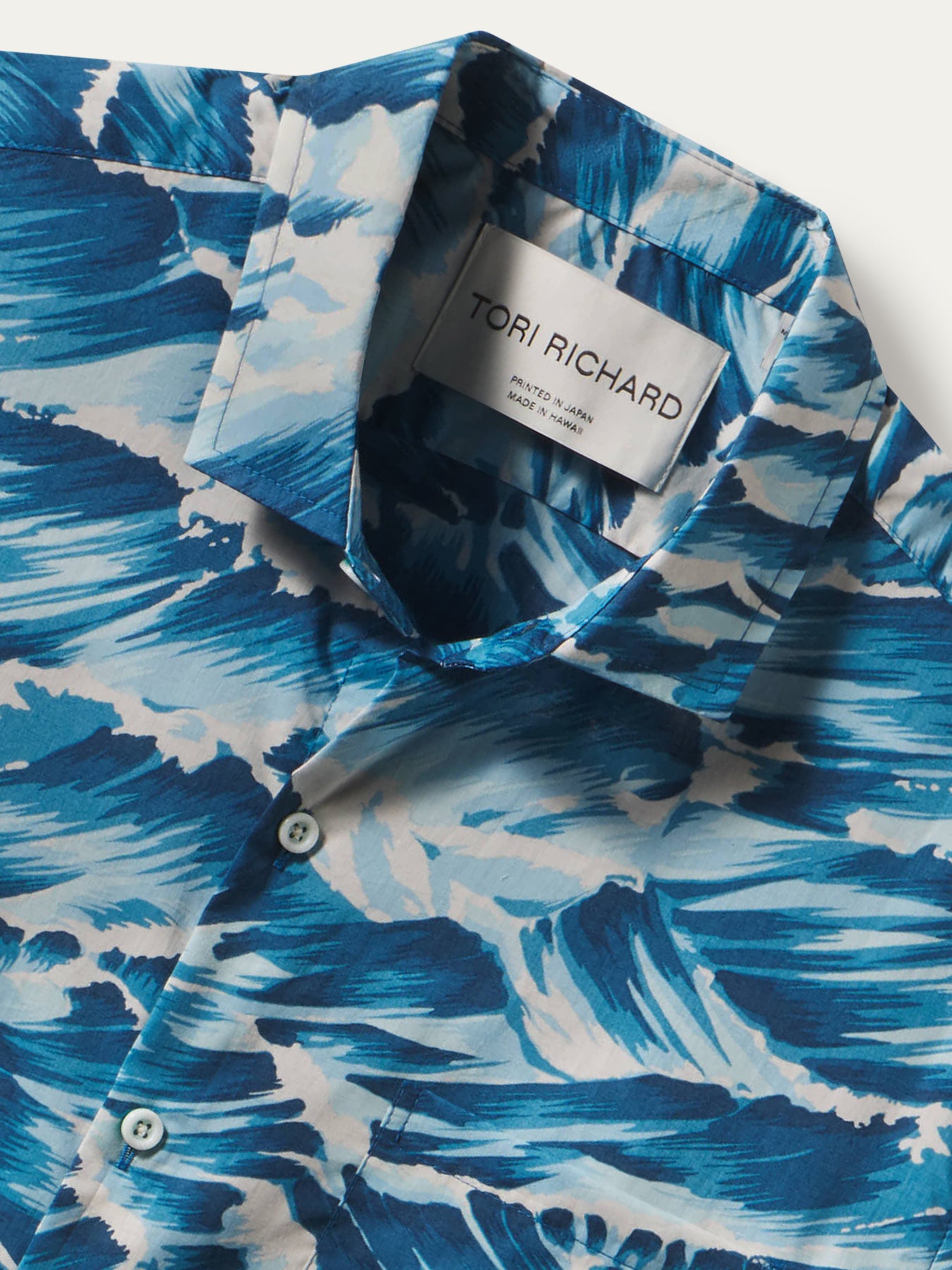 Close-up of a blue and white abstract patterned button-down shirt by Tori Richard, showing the collar label and part of the front placket.