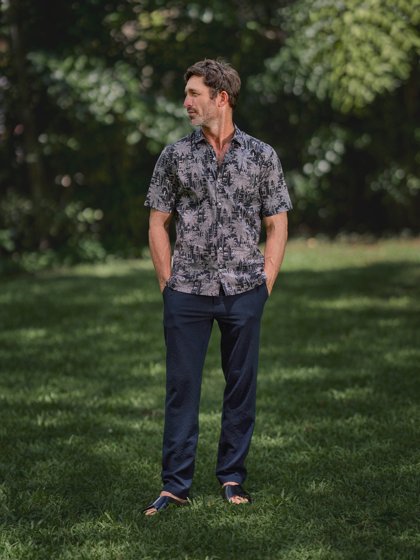 Grey and black palm tree print Royal Stay short-sleeve shirt with navy trousers, full-length view.{{/AltText}}.