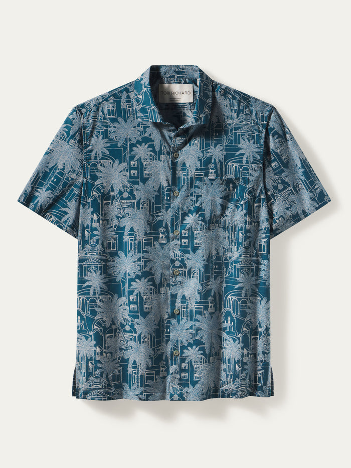 Blue shirt with white palm tree and Royal Hawaiian Resort building print, front view shown in both images.