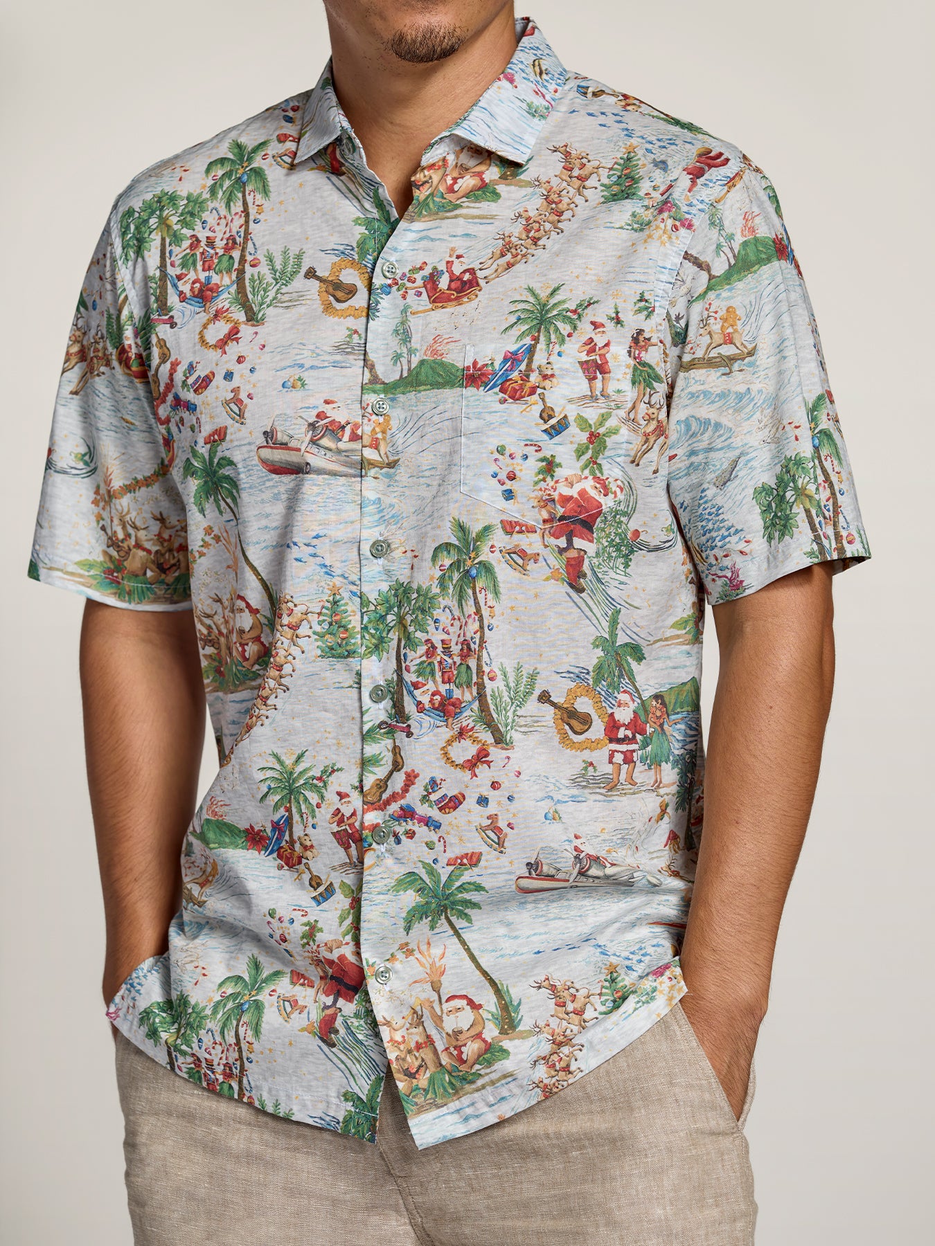 Red and white tropical and Santa-print short-sleeve shirt, man standing with hands in pockets.