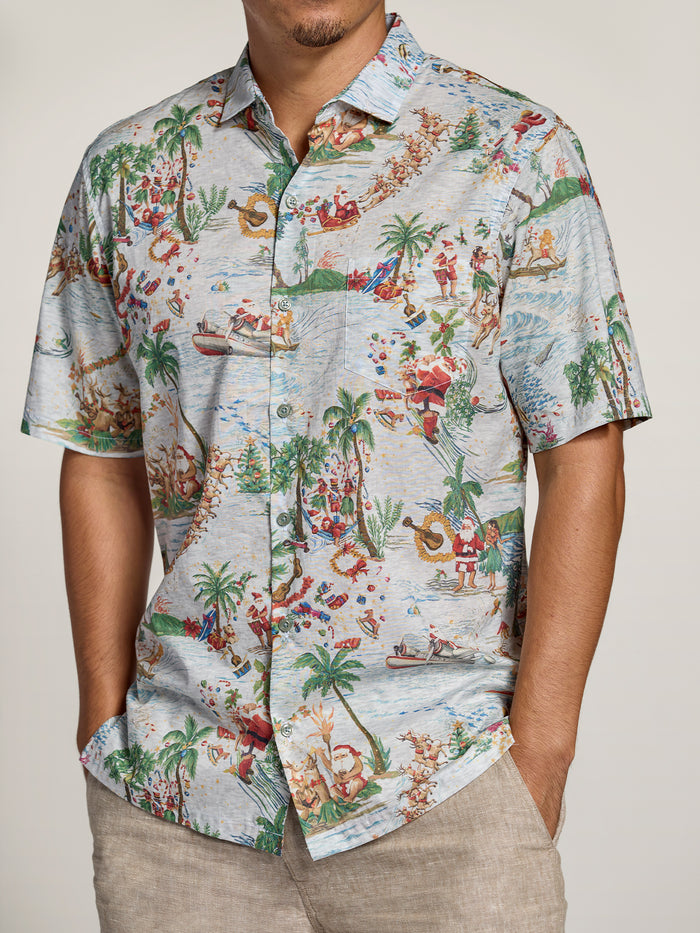 Red and white tropical and Santa-print short-sleeve shirt, man standing with hands in pockets.