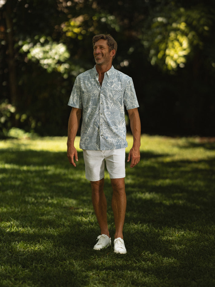 Green/blue leafy-print Tradewind Technology® shirt with white shorts, full-body outdoor view.