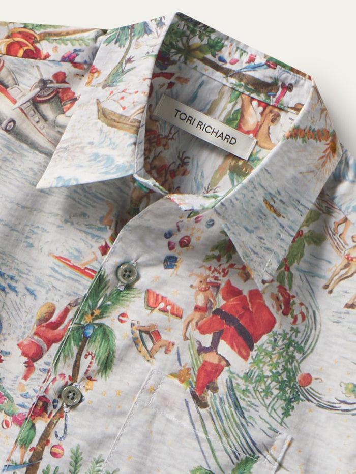 Red, green, and white Santa and palm print cotton short-sleeve shirt, close-up of fabric detail.