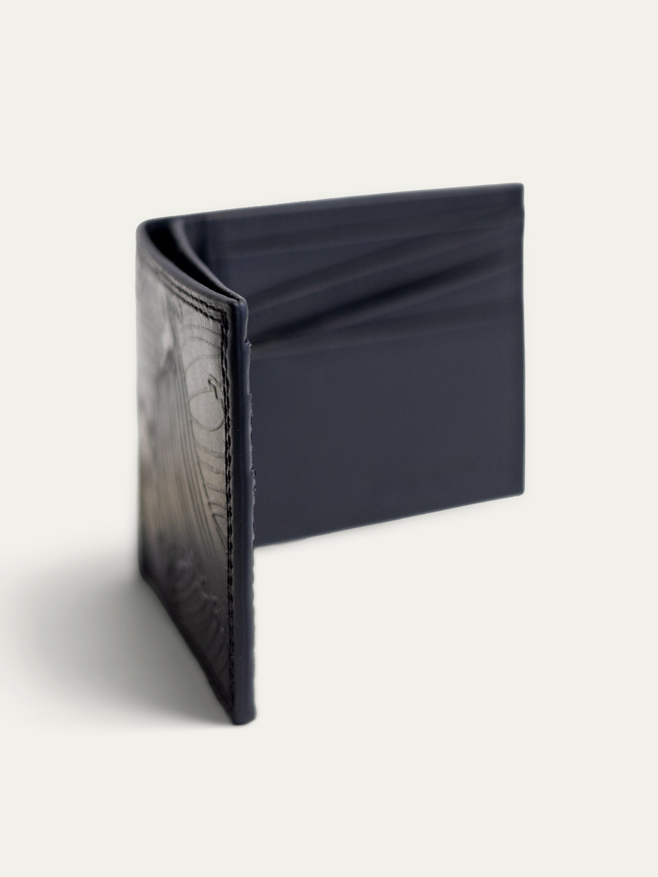 A dark navy blue leather bifold wallet with a textured alligator or crocodile pattern on the front cover, shown standing open against a light off-white background.