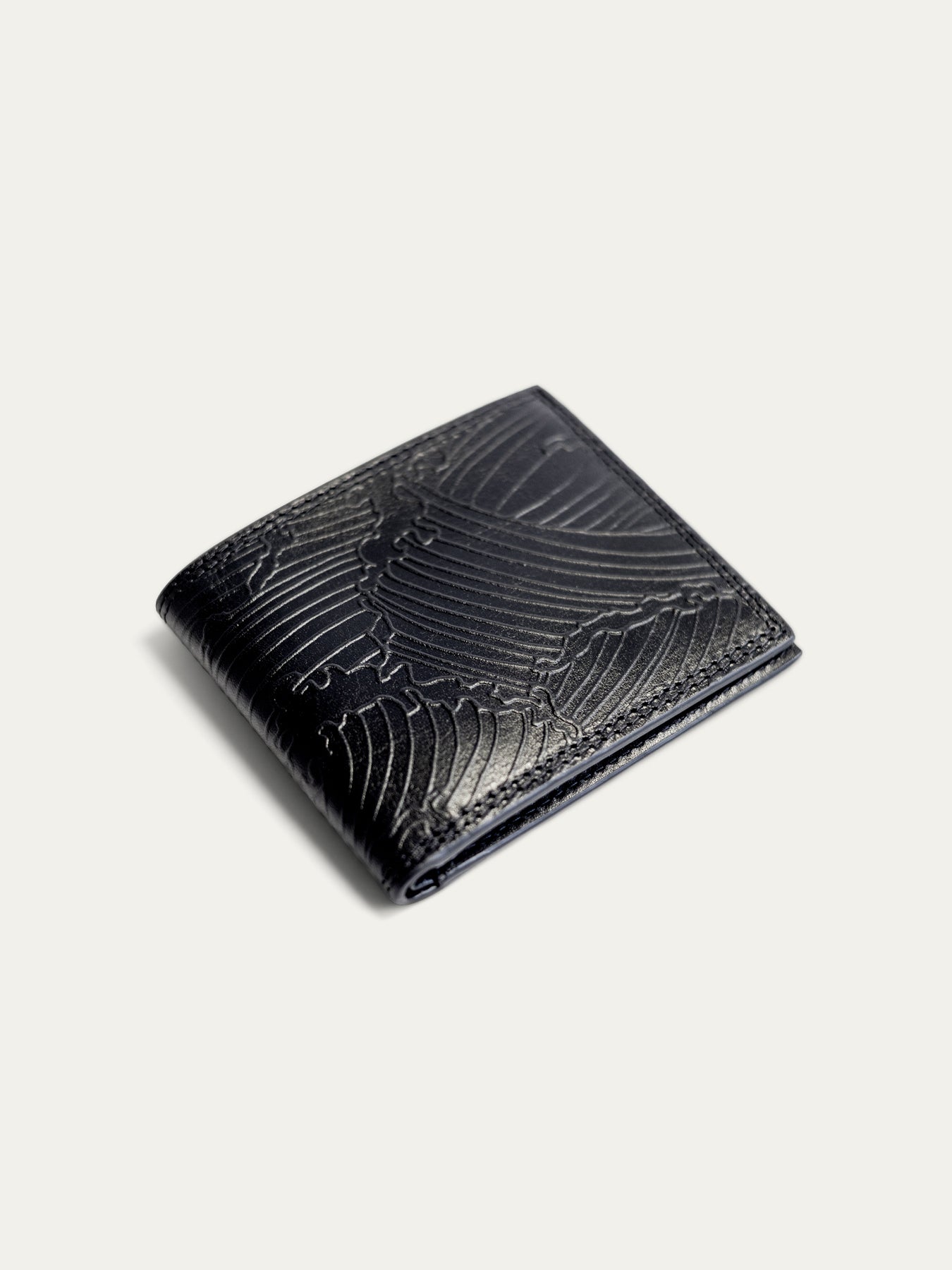 A black leather bifold wallet with an embossed wave pattern, shown on a light off-white background.