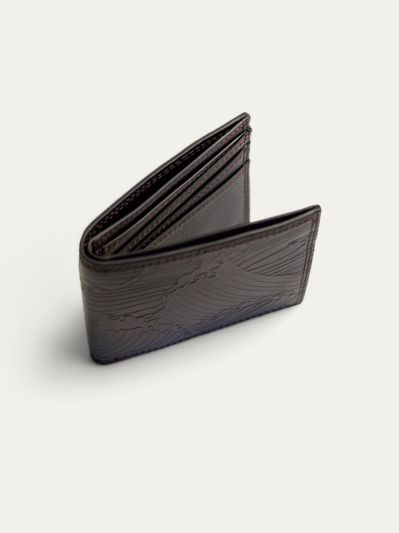 A dark brown leather bi-fold wallet with an embossed wave pattern, shown open on a light off-white background.