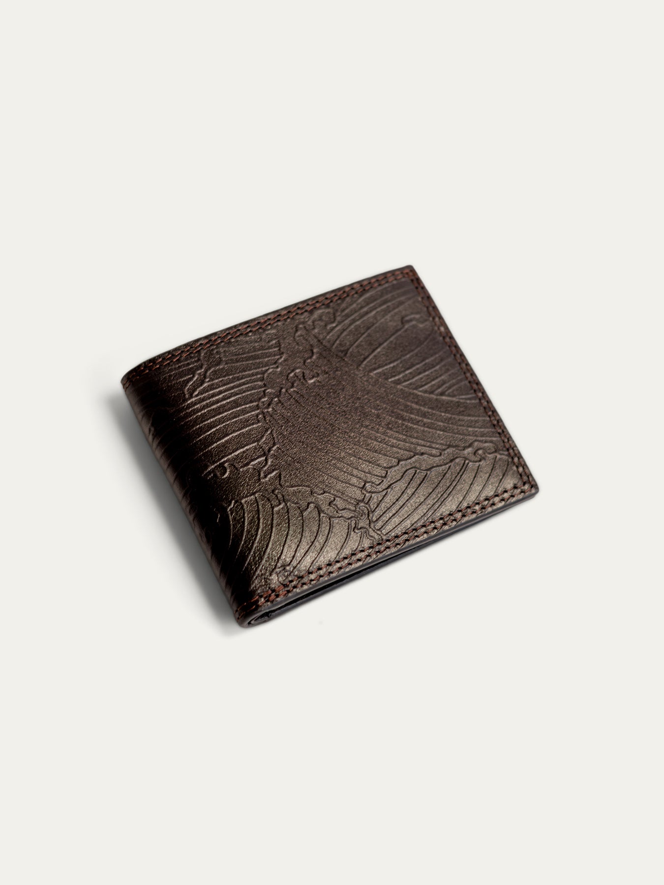 A dark brown leather bifold wallet with an embossed eagle design on the front, shown on a light off-white background.