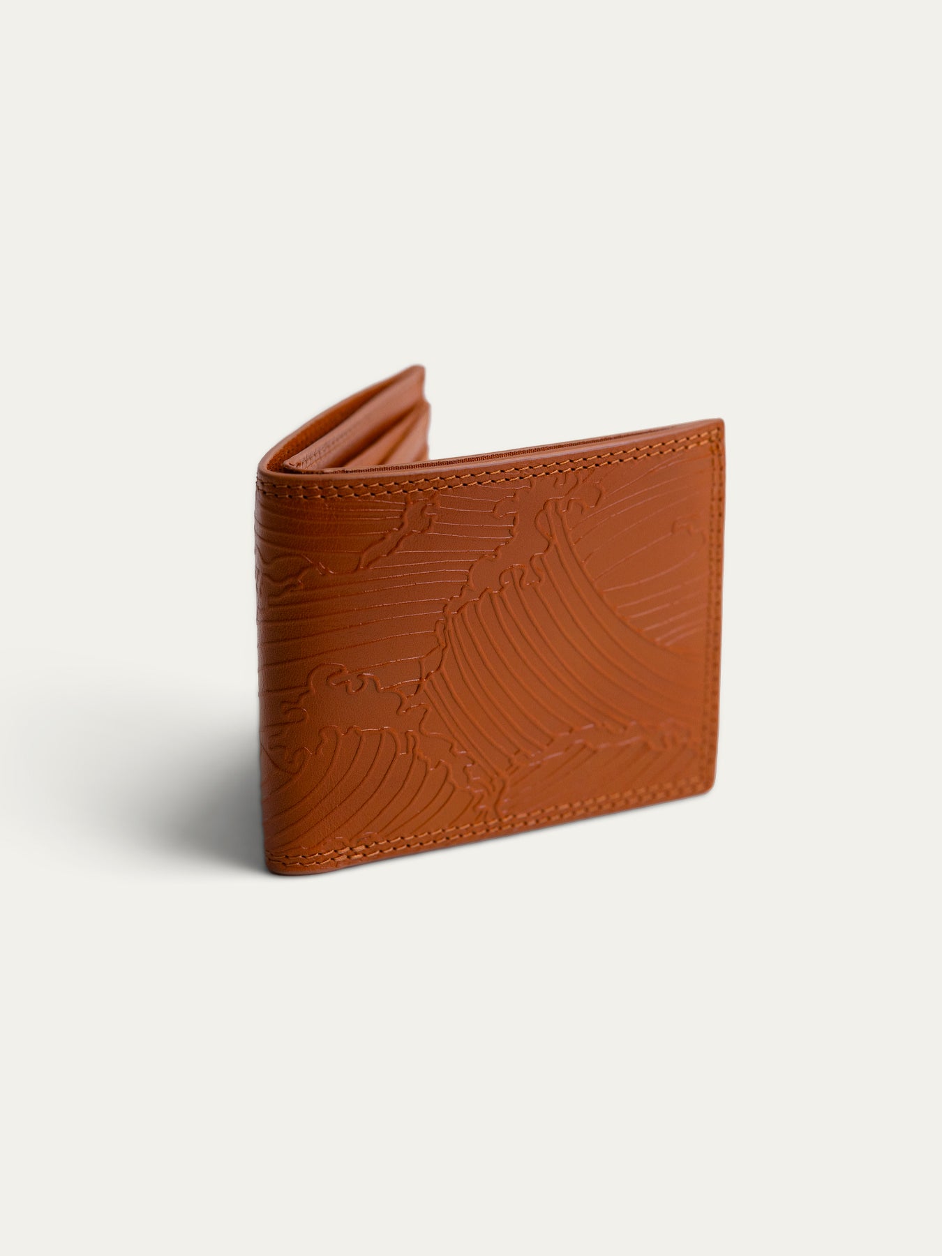 A brown leather bi-fold wallet with an embossed wave pattern, shown open on a light off-white background.