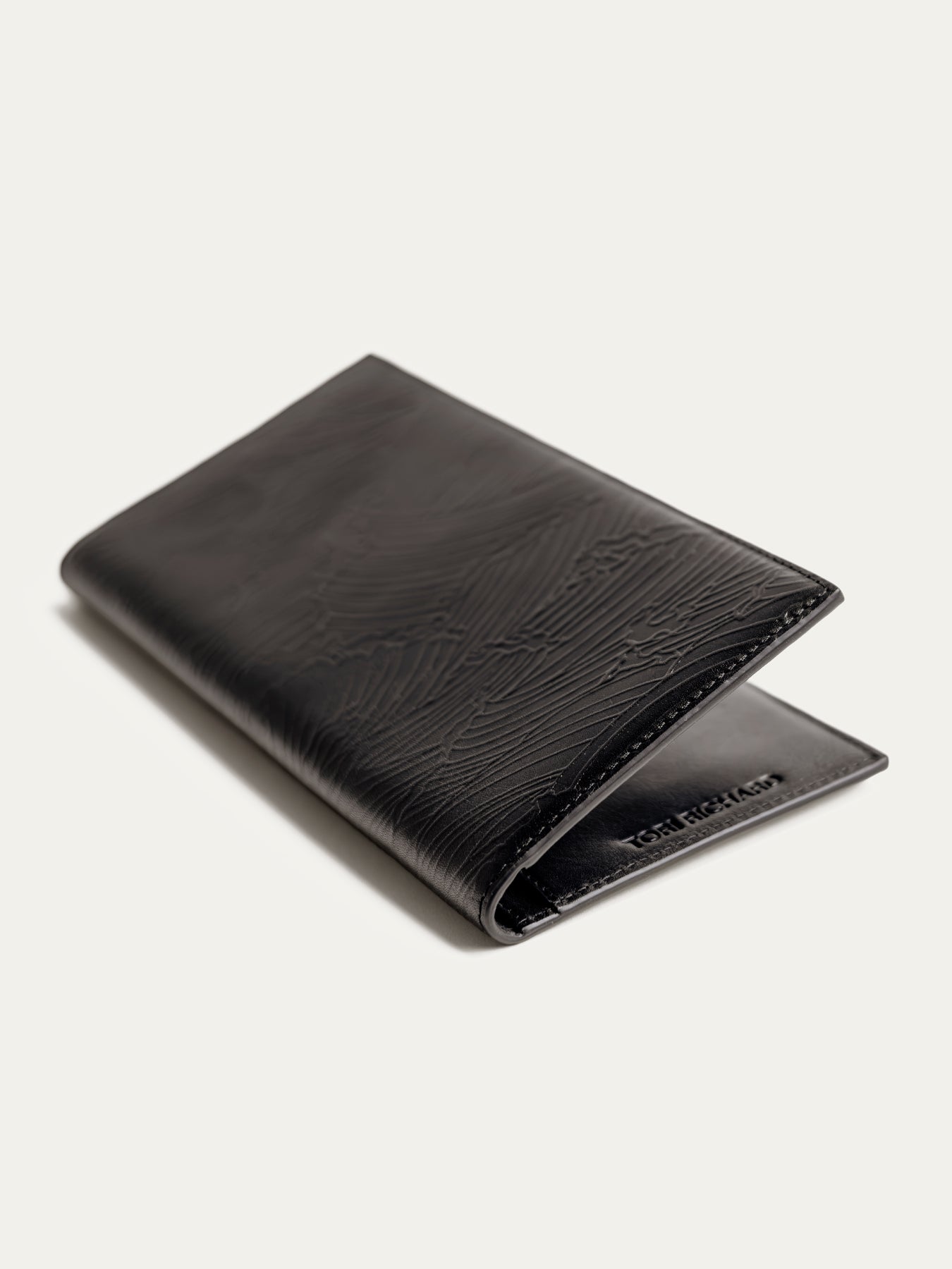 Black textured leather travel wallet, partially open exterior view.