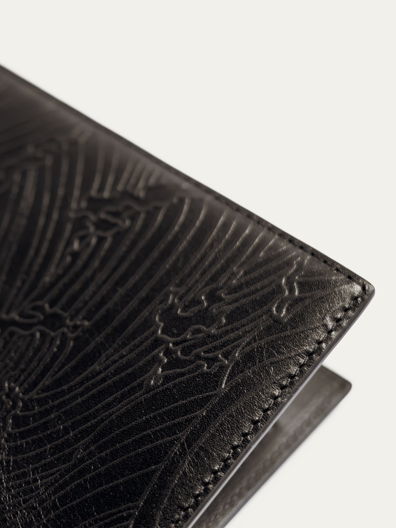 Black embossed-leather travel wallet with edge stitching, close-up view.