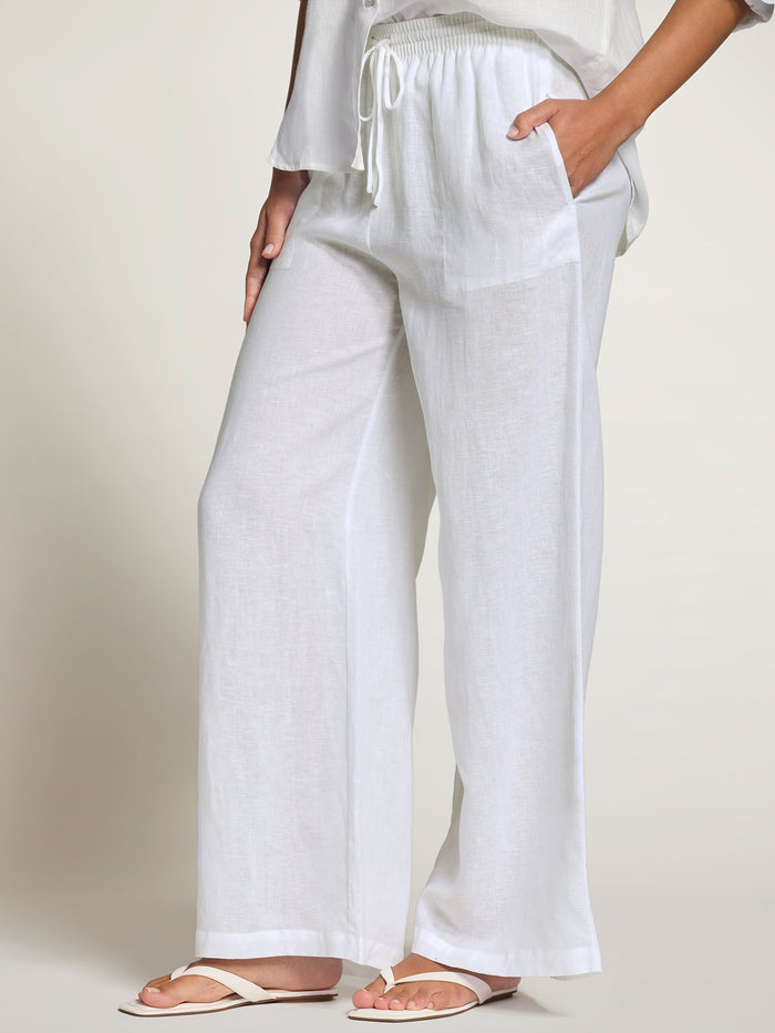 White linen pants with drawstring waist and pockets, shown in full front view.