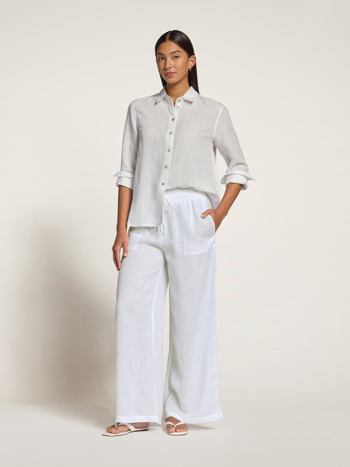 White button-up shirt and light floral linen pants, side view with hand in pocket.