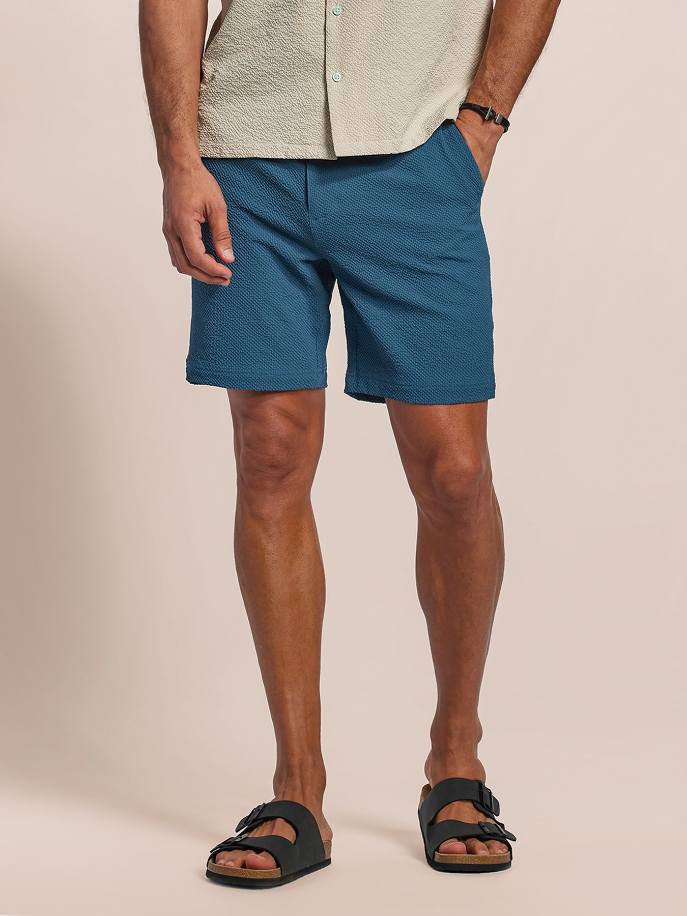 Blue solid shorts with belt loops and side pockets model front view with black sandals.