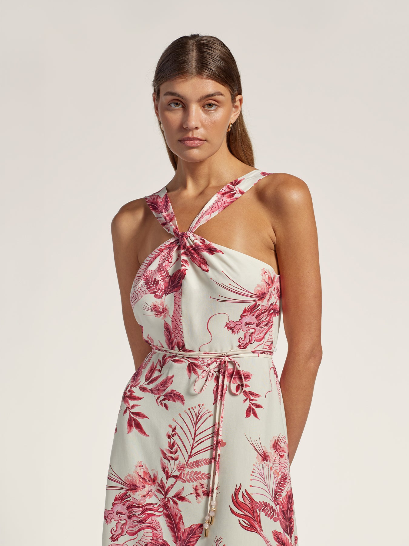 Pink floral-print dress with cross-strap neckline and waist tie, front view shown in both images.