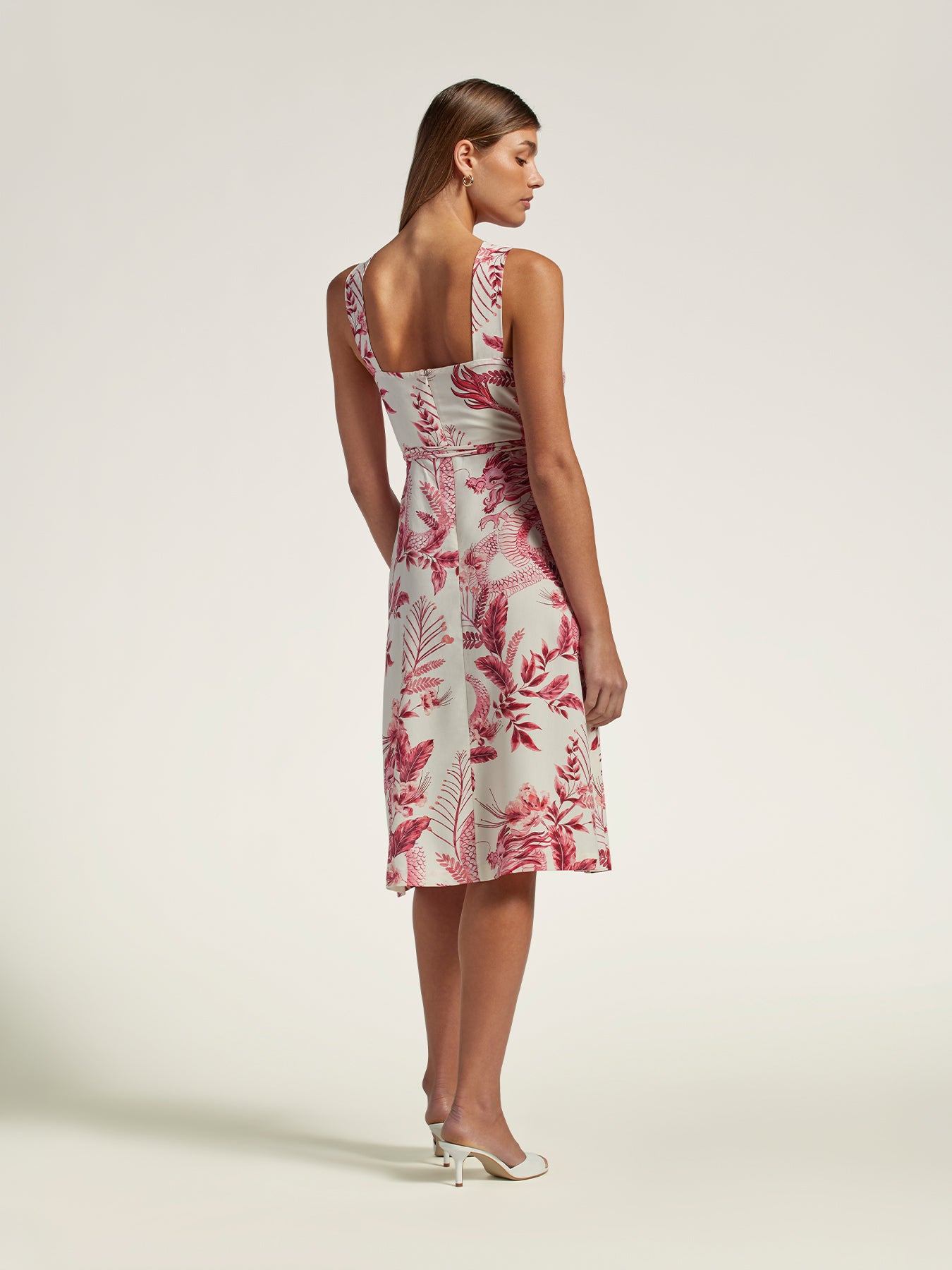 Woman in white and red floral-print sleeveless sundress, profile view (Image 1 & 2).