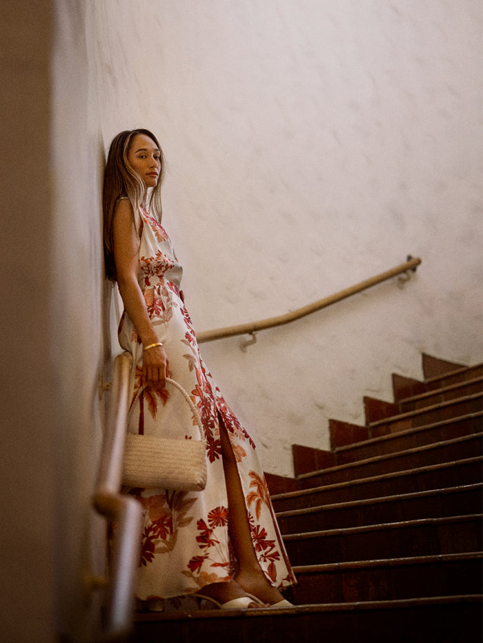 White floral-print V-neck maxi dress with a front slit, side view on a staircase.{{/AltText}}.
