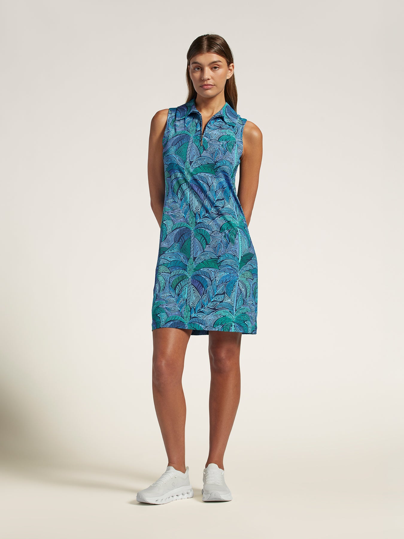 Blue sleeveless solid dress with white sneakers, full body view on plain background