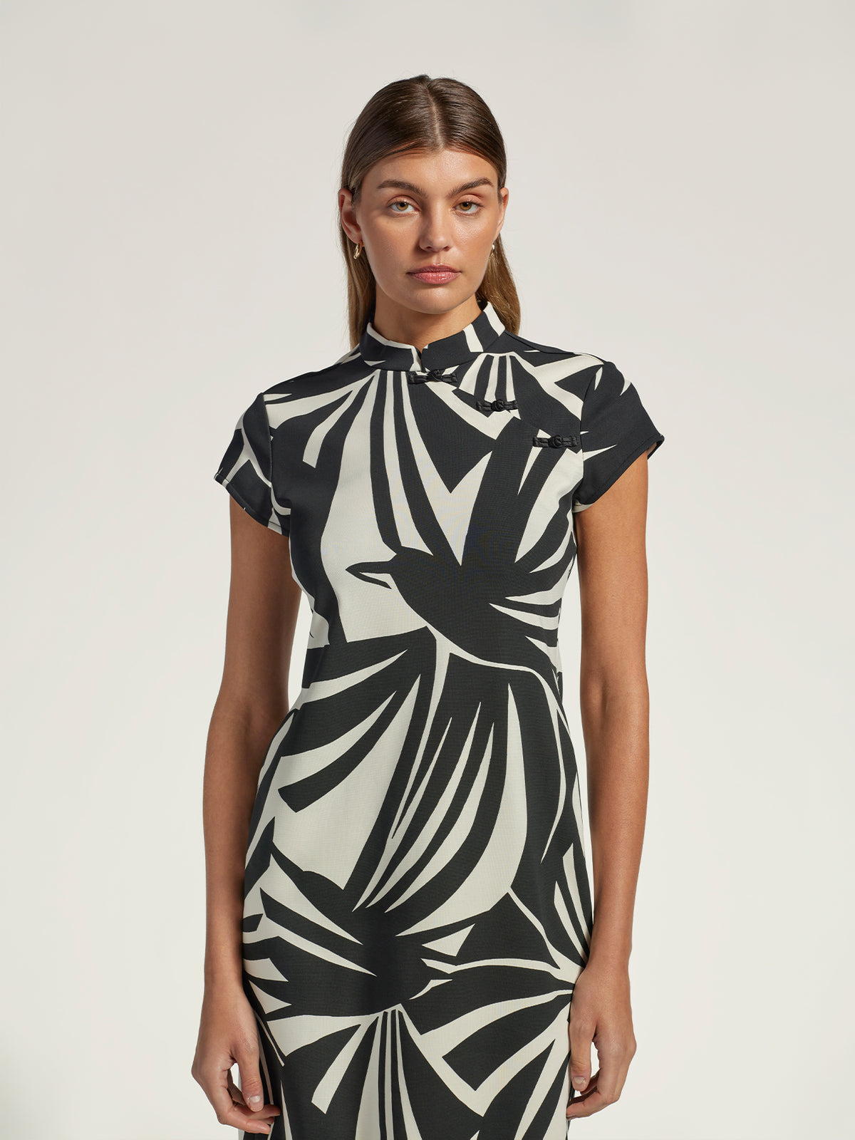 Black solid midi dress with mandarin collar, front view on woman, plain background.