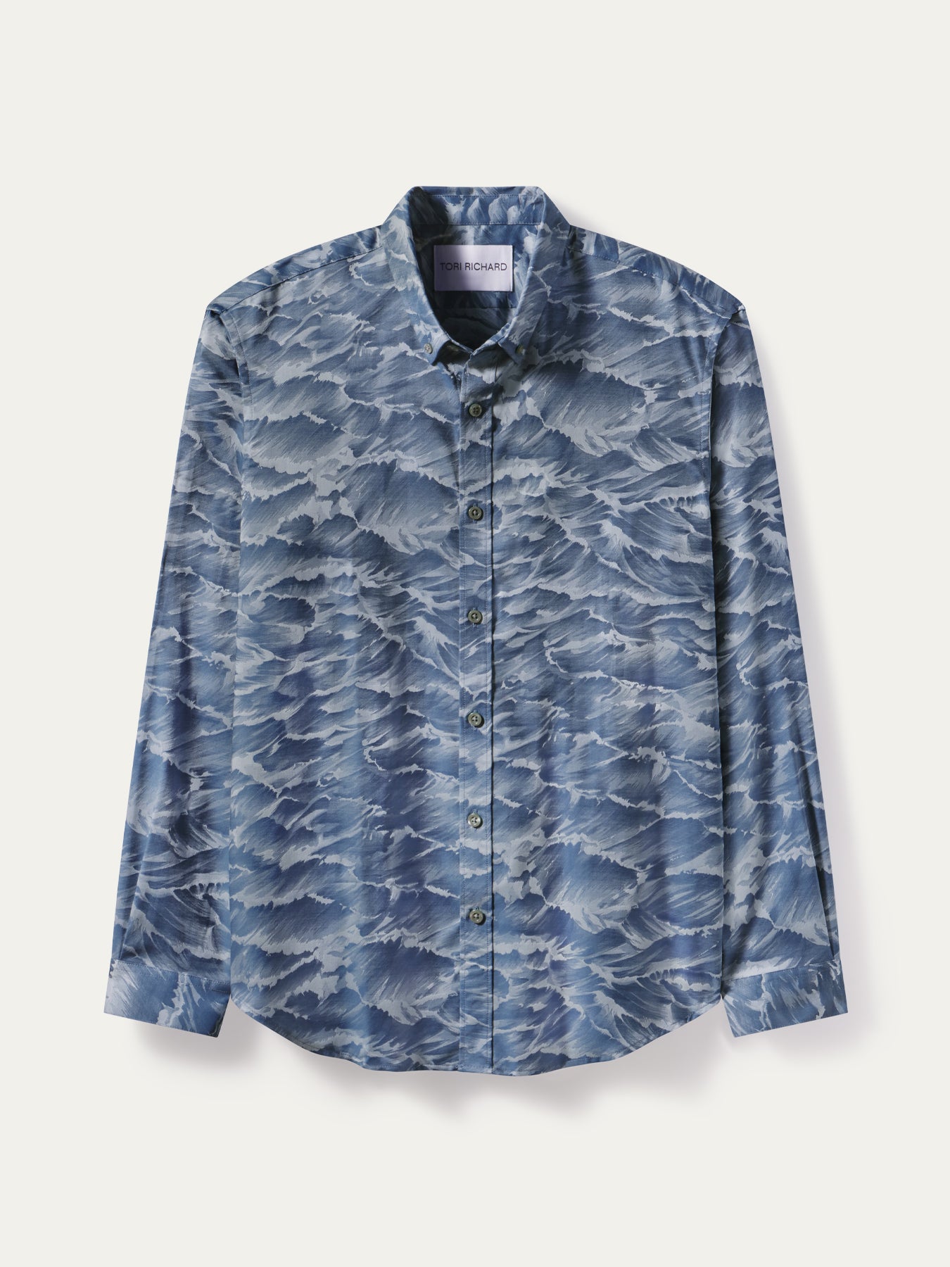 A long-sleeve button-up shirt with a blue and white wave pattern, displayed flat against a light off-white background.