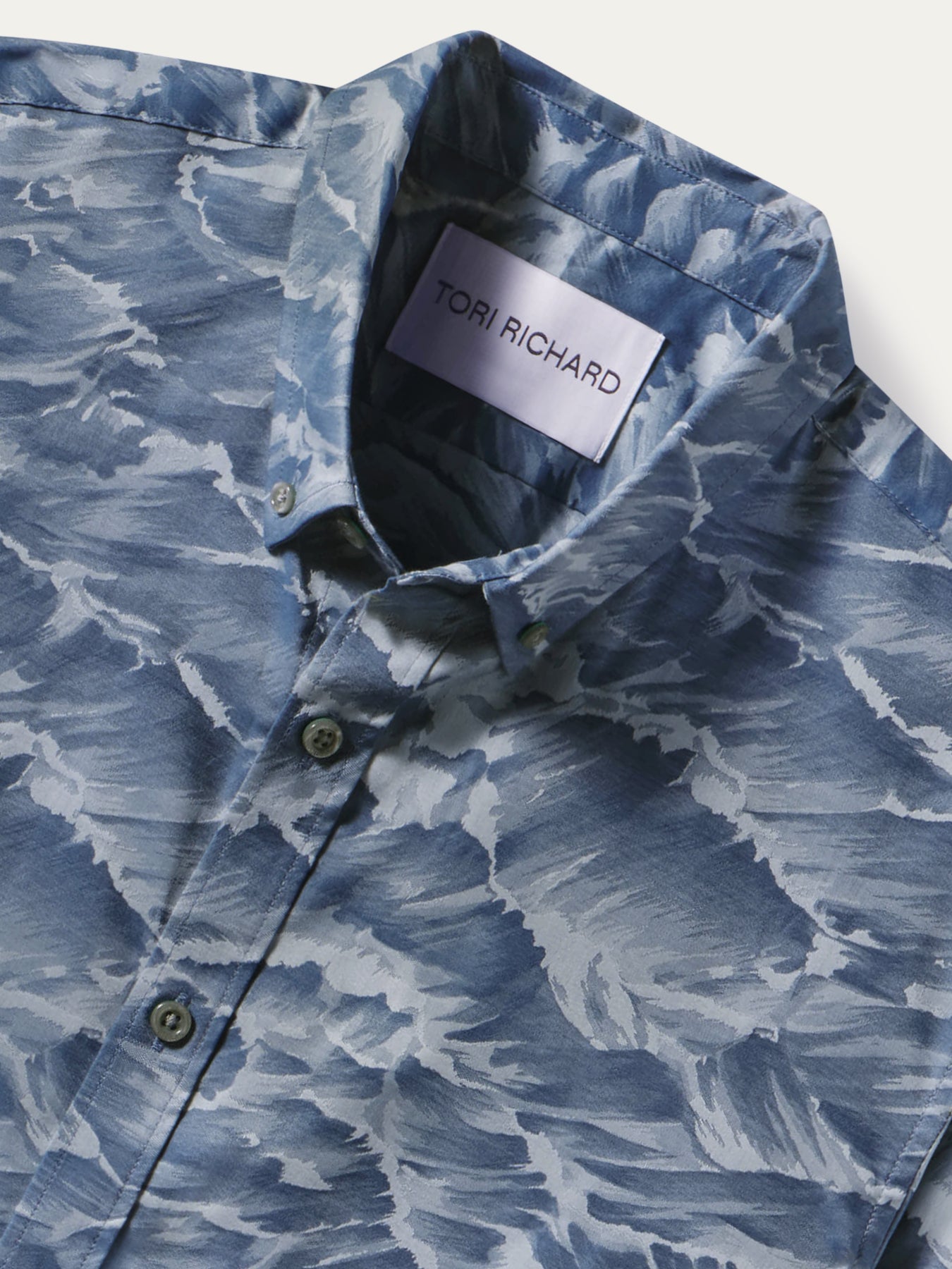 A close-up of a blue and white abstract patterned button-down shirt by Tor Richard, showing the collar label and front buttons.