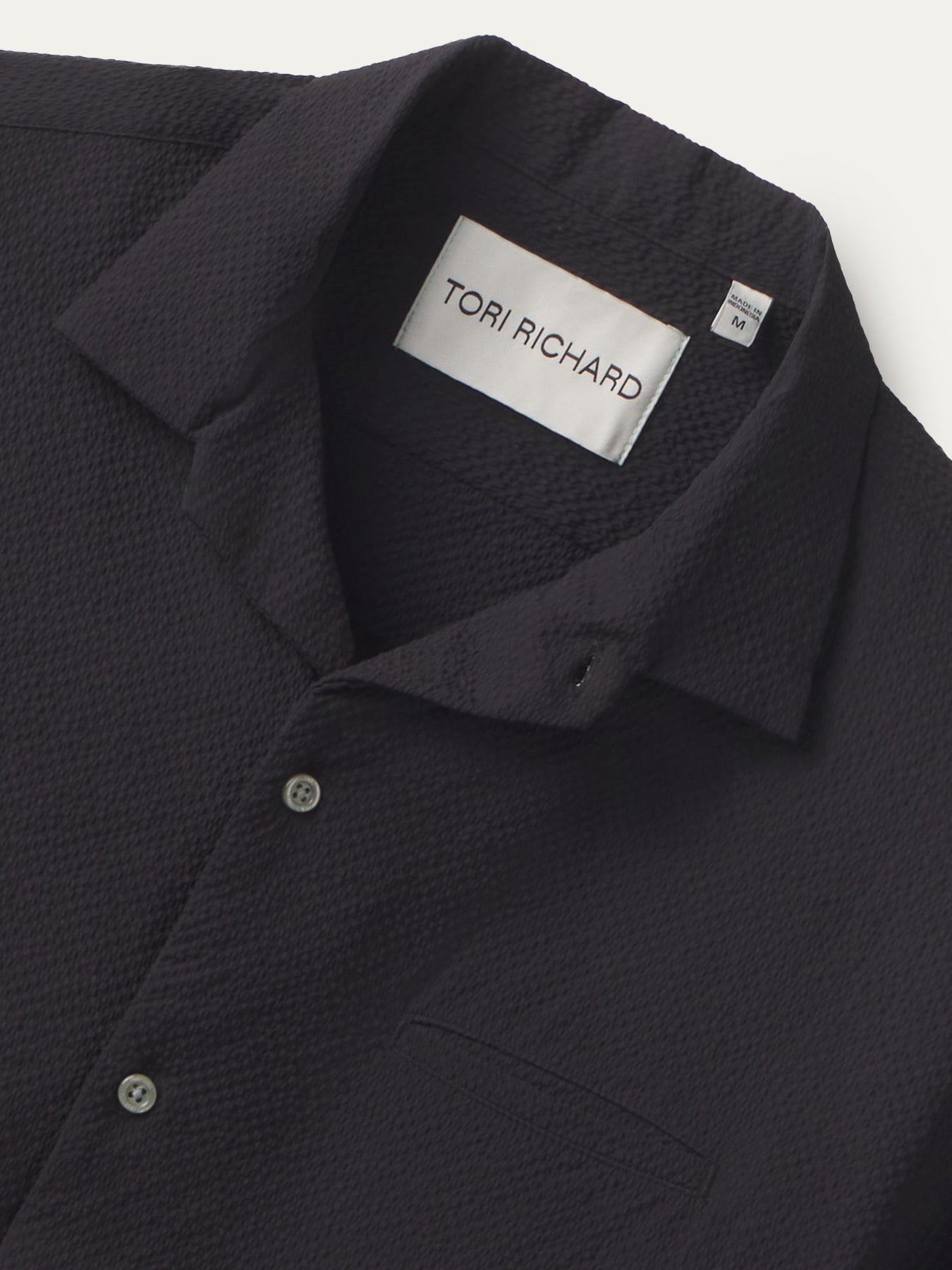 Black textured collared shirt with chest pocket, front view .