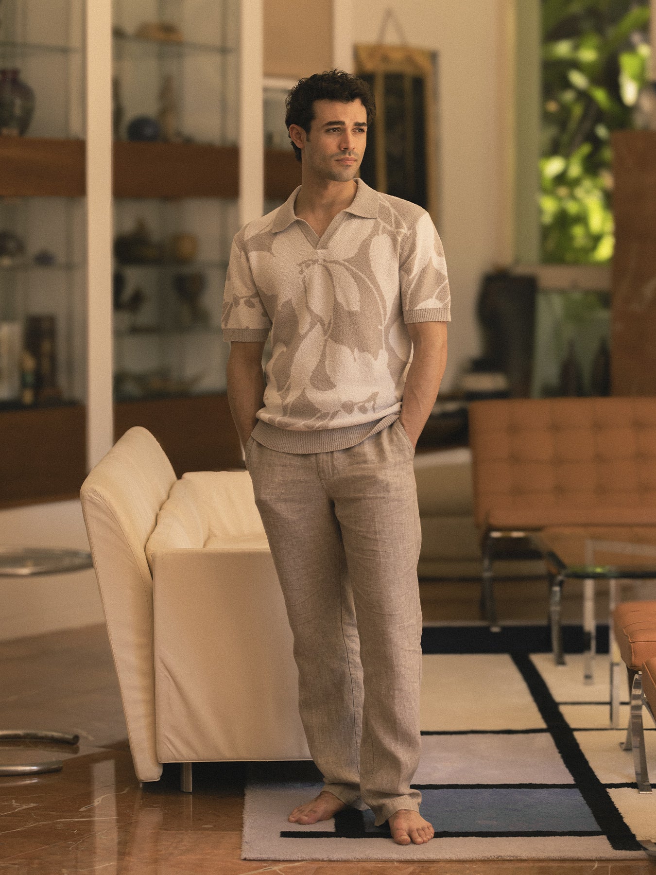 Cream/multi-color retro-patterned boucle polo shirt, front view on man by cream sofa.