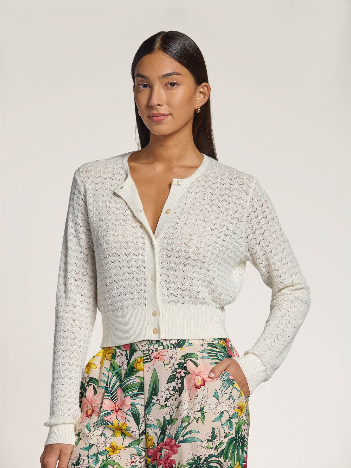 White lace pointelle cardigan and multicolor floral-print pants, full front view.