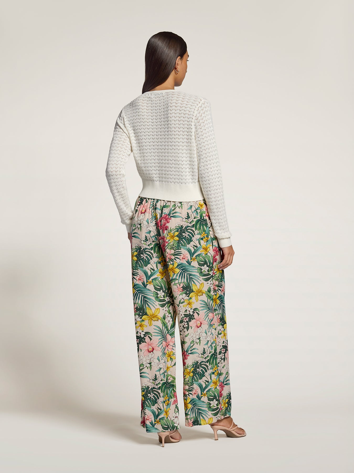 White lace pointelle cardigan and multicolor floral wide-leg pants, back view.