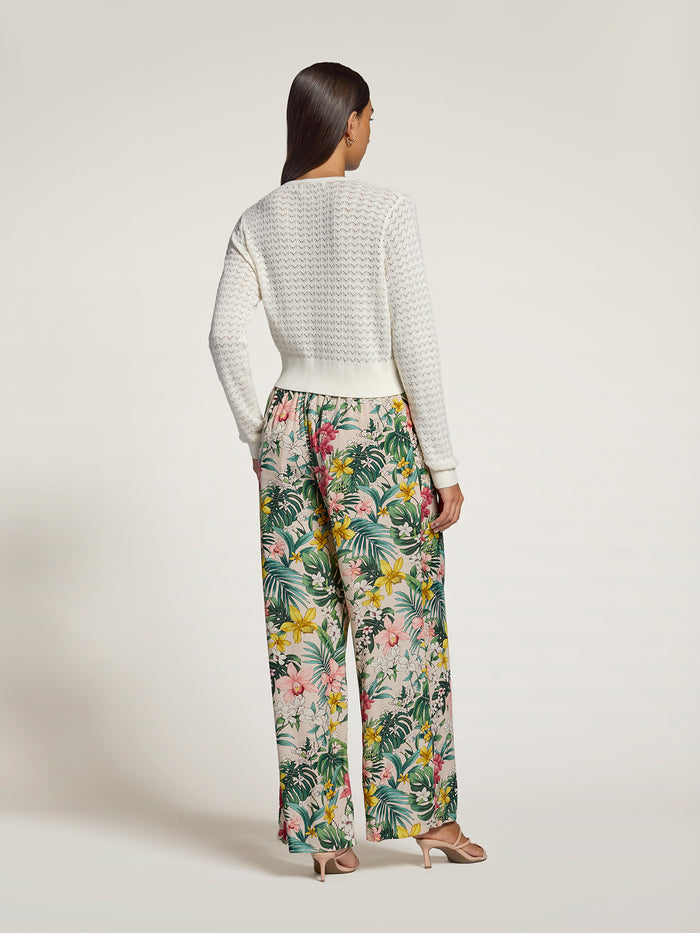 White lace pointelle cardigan and multicolor floral wide-leg pants, back view.