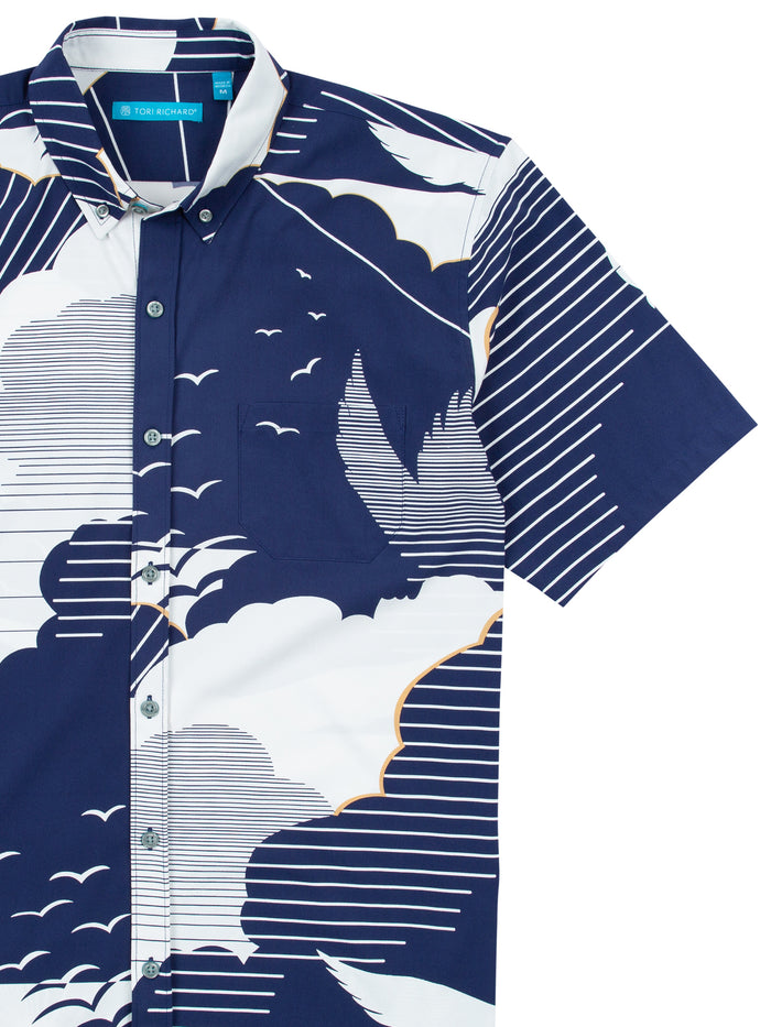 Navy short-sleeve shirt with white and orange clouds, birds, and stripes pattern, front view.