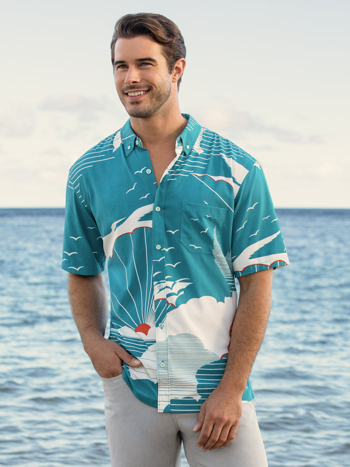 Teal patterned short-sleeve shirt, man standing by the ocean, hand in pocket, front view{{/AltText}}.